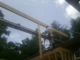 Carpenter setting a ridge beam over a new addition frame — Ice Dam Removal by Roofing Brothers in Riverside